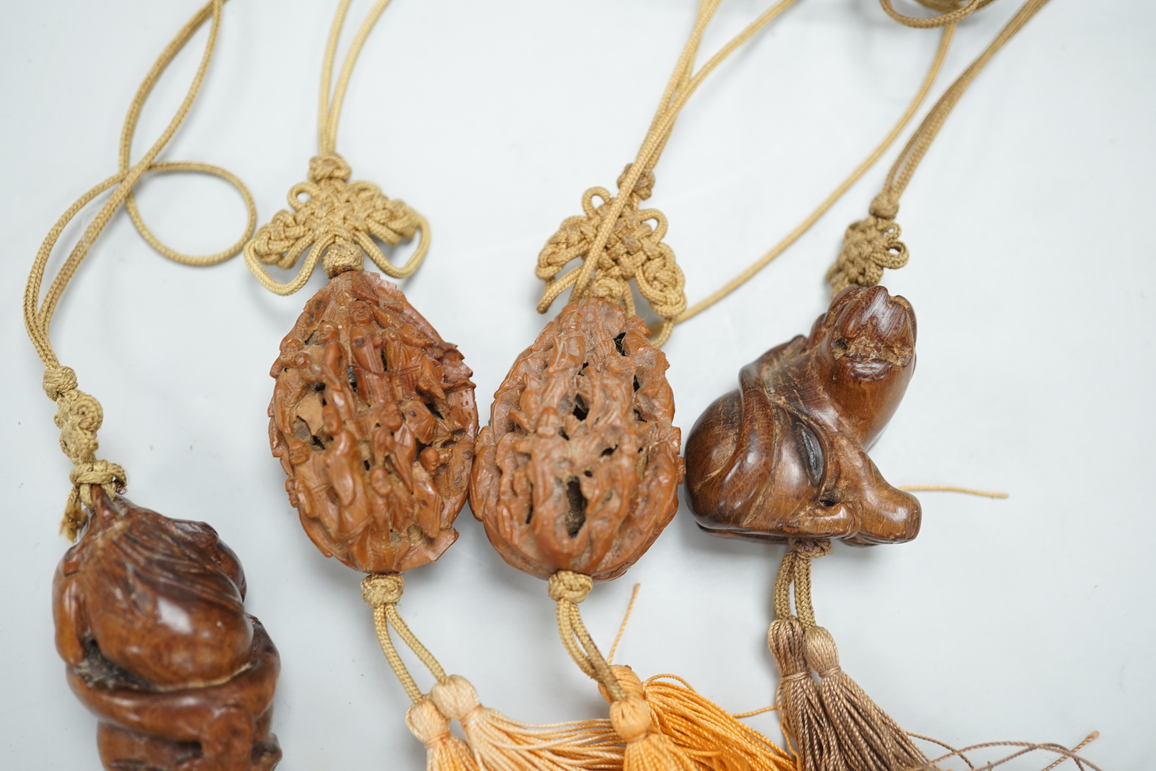 Two Chinese peach stone carvings and two carved wood toggles on a silk cord